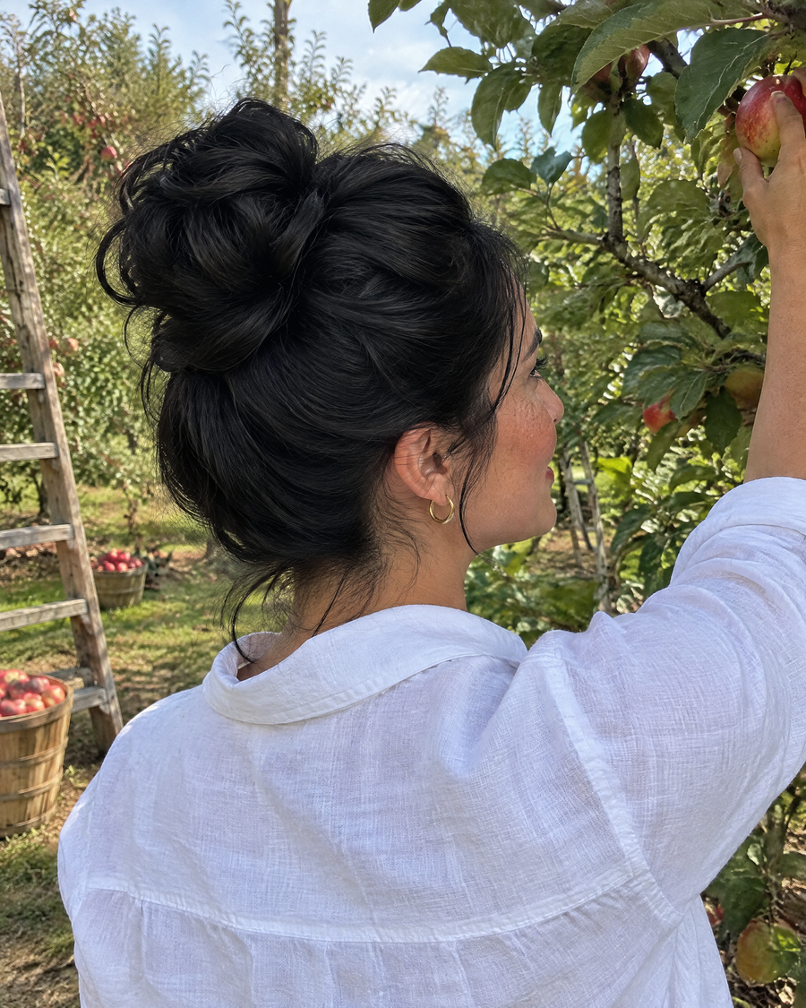Woman wearing the JuvaBun Messy Bun in Black while apple picking