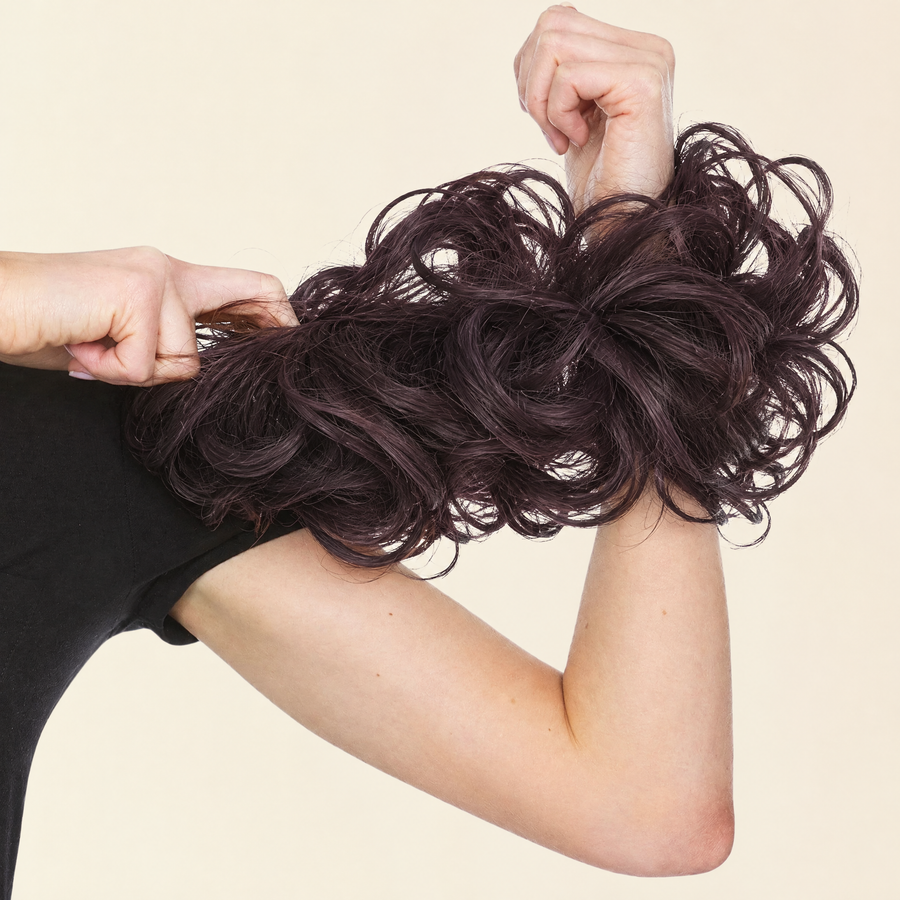 Hands stretching the JuvaBun Messy Bun in Black Cherry to show the scrunchie band