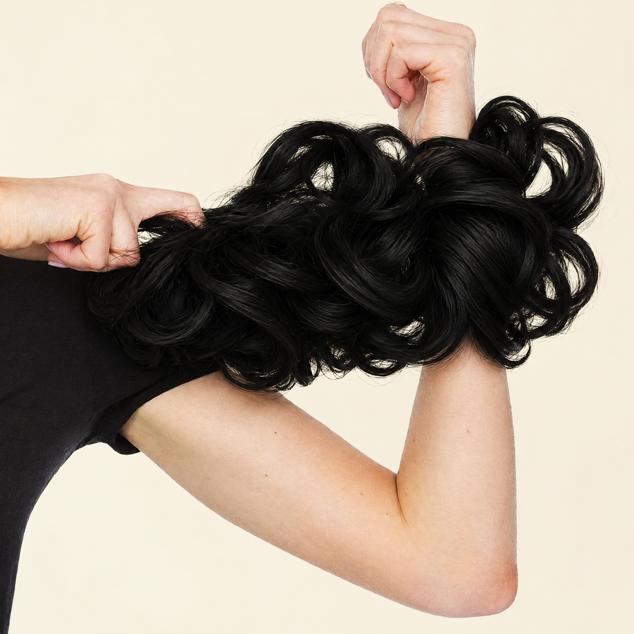 Hands stretching the JuvaBun Messy Bun in Black to show the scrunchie band