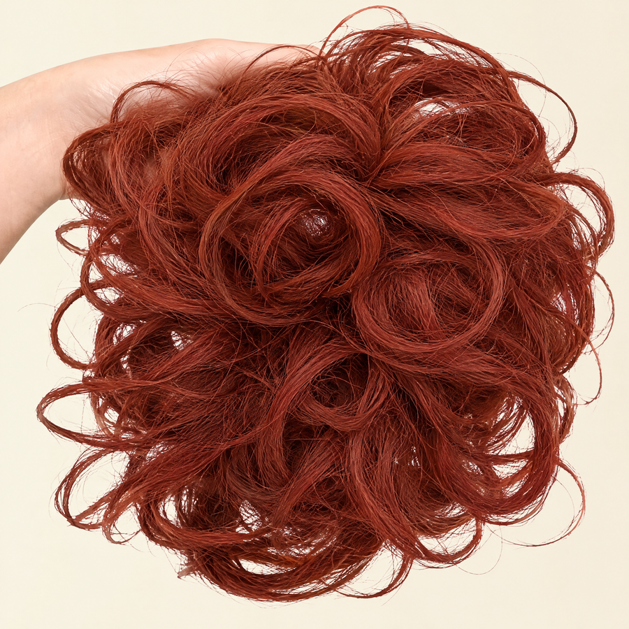Hand holding the full JuvaBun Messy Bun in Copper Red