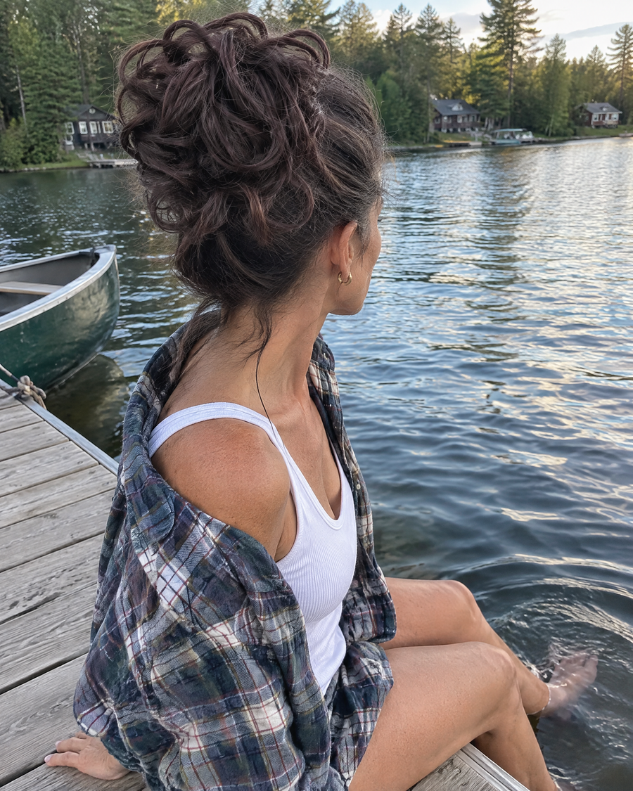 Woman wearing the JuvaBun Messy Bun in Dark Brown on a lake dock