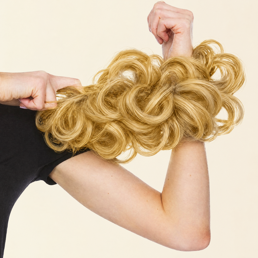 Hands stretching the JuvaBun Messy Bun in Gold to show the scrunchie band