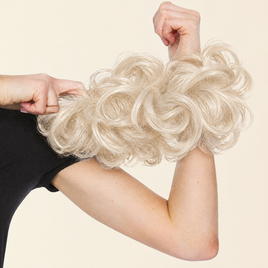 Hands stretching the JuvaBun Messy Bun in Platinum Blonde to show the scrunchie band