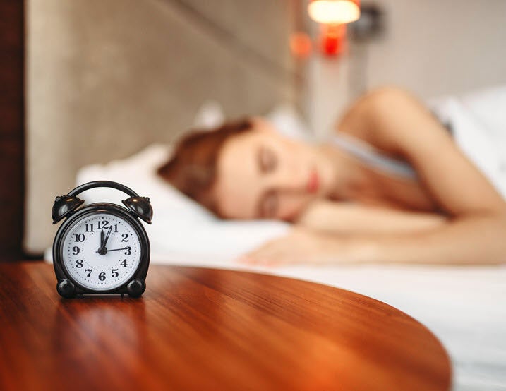 woman sleeping in while alarm is ringing