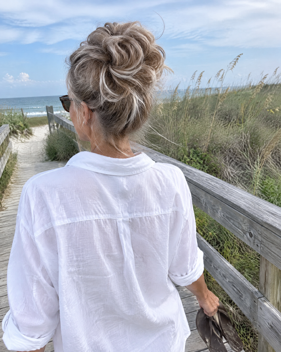 Woman wearing the JuvaBun Messy Bun in Beach Blonde on a dune boardwalk