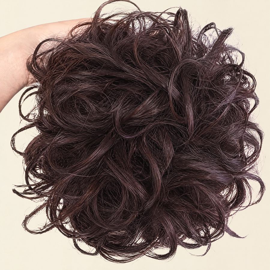 Hand holding the full JuvaBun Messy Bun in Black Cherry