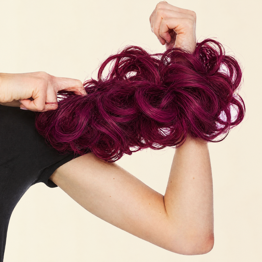 Hands stretching the JuvaBun Messy Bun in Burg to show the scrunchie band