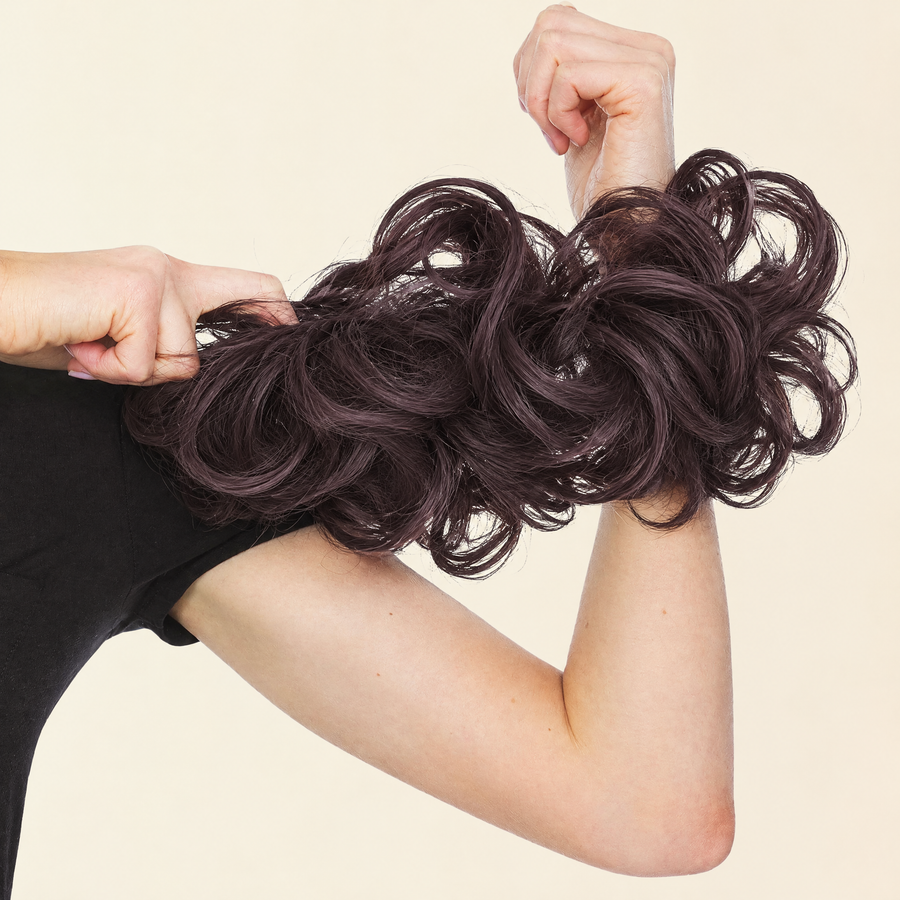 Hands stretching the JuvaBun Messy Bun in Dark Brown to show the scrunchie band