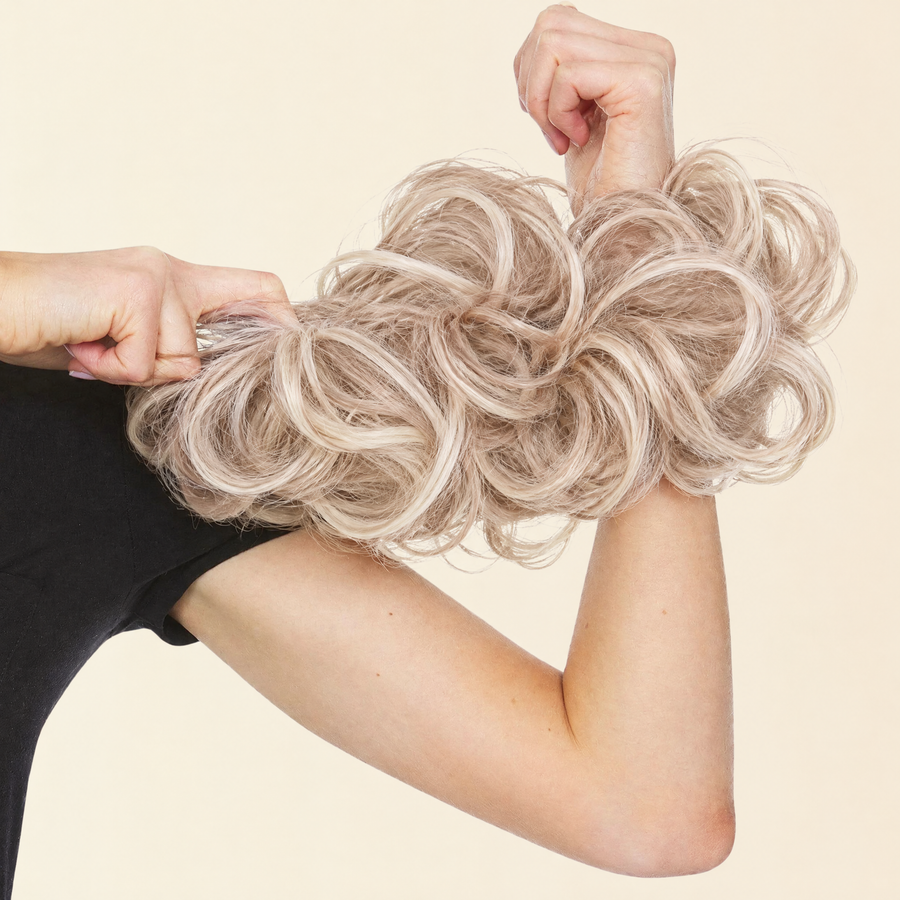 Hands stretching the JuvaBun Messy Bun in Light Brownish Blonde to show the scrunchie band
