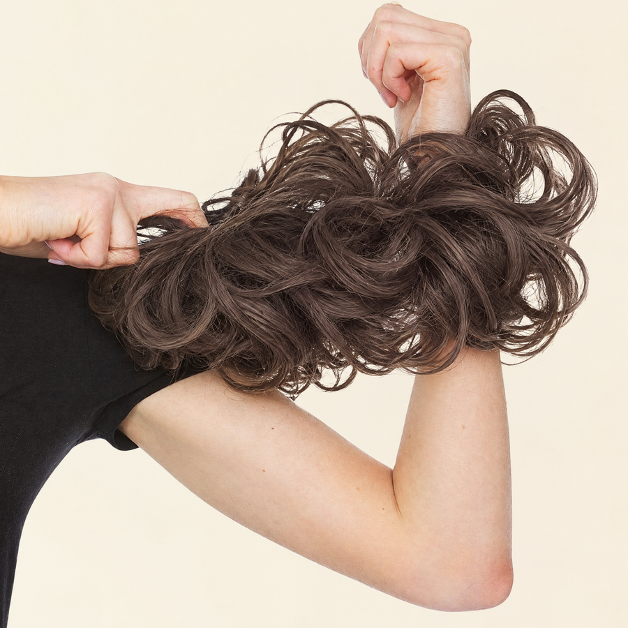 Hands stretching the JuvaBun Messy Bun in Medium Brown to show the scrunchie band