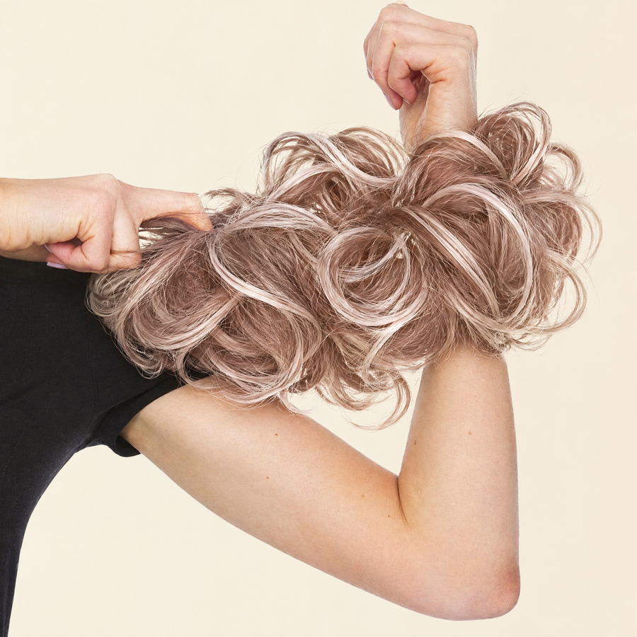 Hands stretching the JuvaBun Messy Bun in Strawberry Honey Blonde to show the scrunchie band